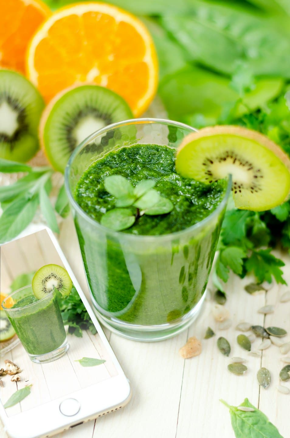 Green smoothie with kiwi and mint on wood surface.